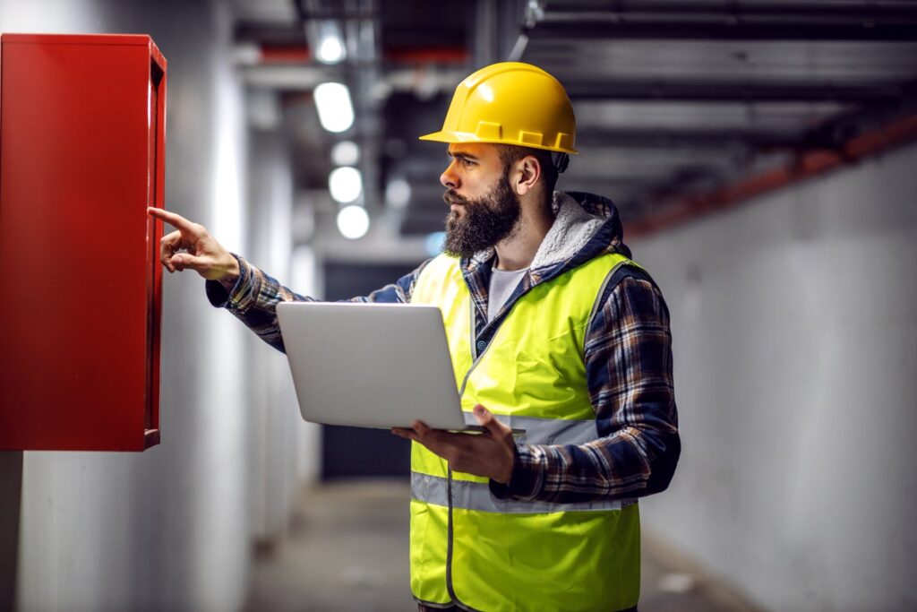 A man in a hard hat examining a box to ensure statutory compliance in facilities management